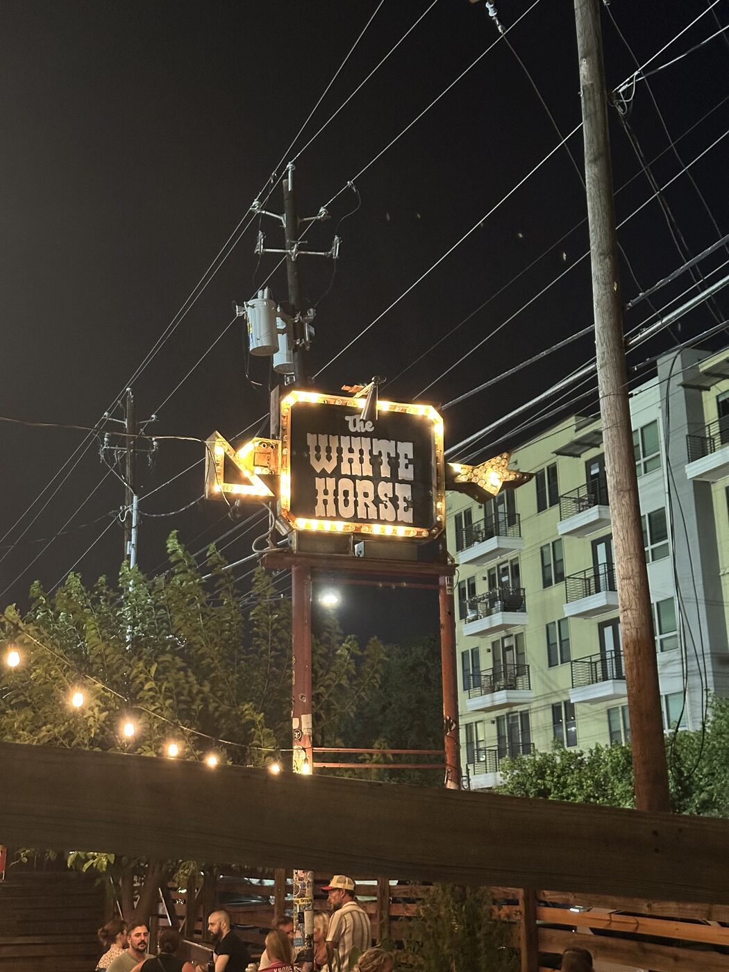 The illuminated White Horse honky-tonk sign glowing against the night sky in East Austin.